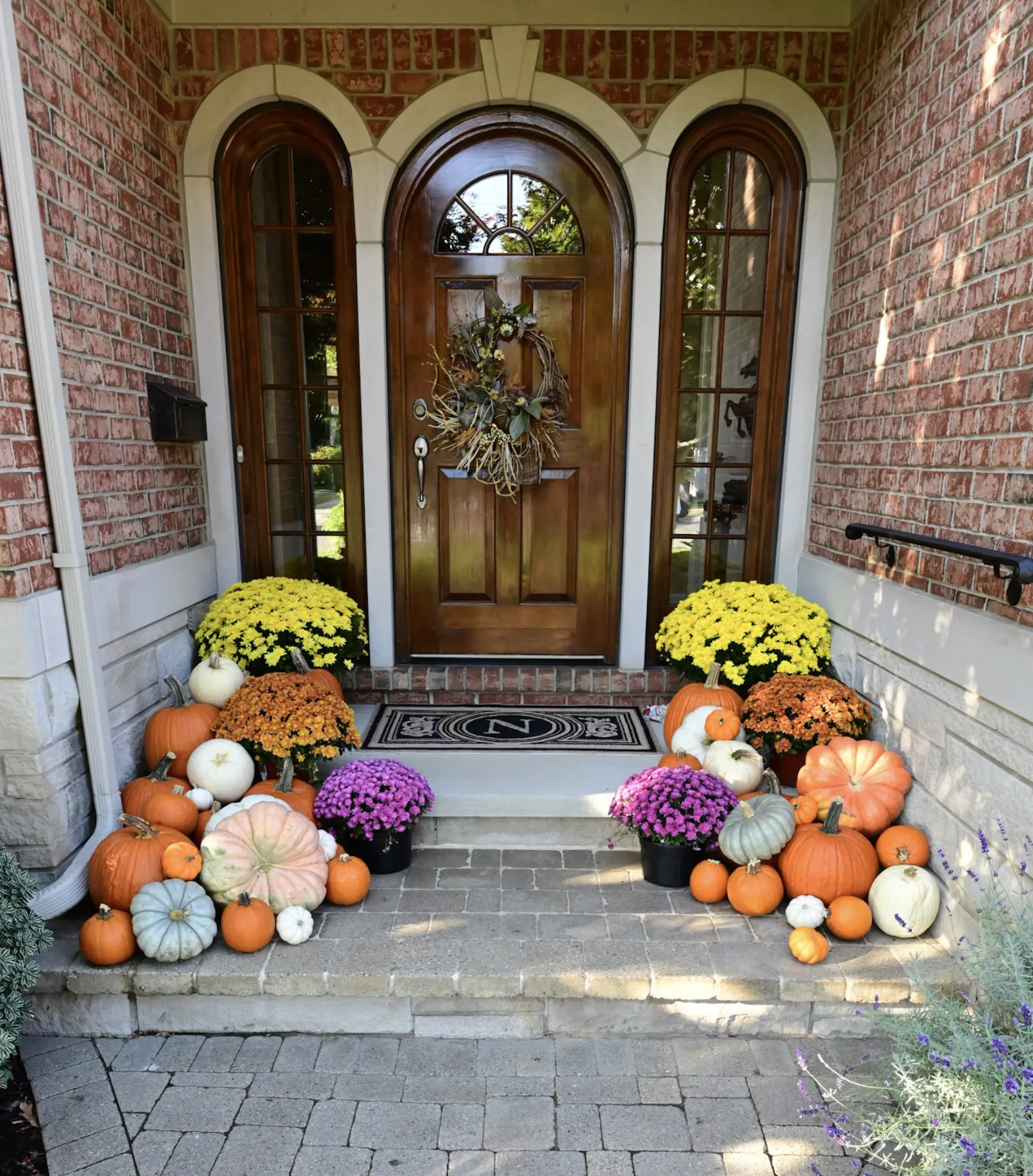 Fall porch decorating with heirloom pumpkins and colorful mums on brick colonial home in Bloomfield Hills MI
