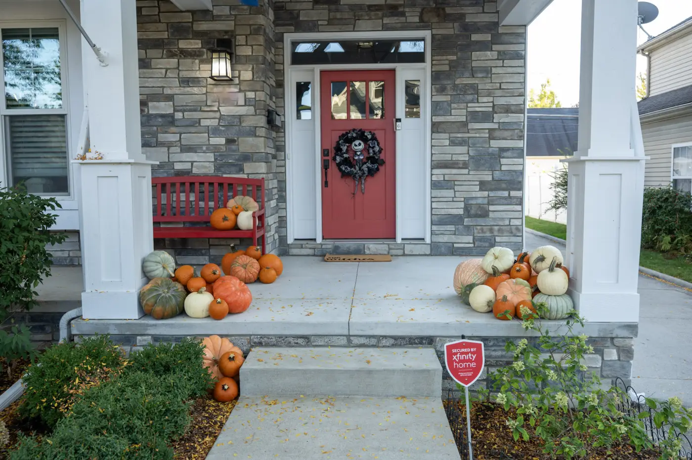 Fall pumpkin display on stone craftsman porch with red door in Royal Oak MI