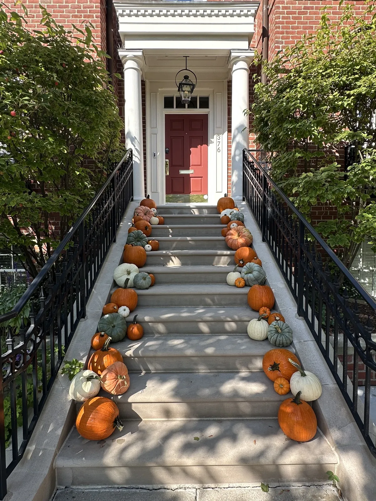 Pumpkin-lined staircase porch decorating with red door brick rowhome in Detroit MI
